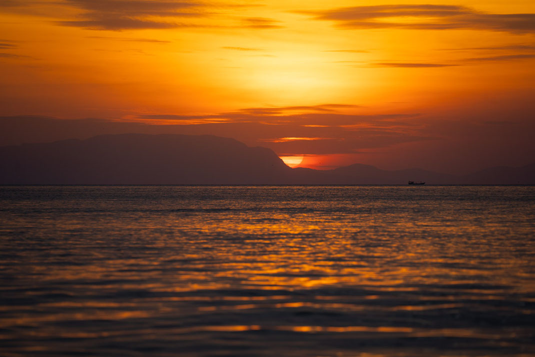 A sunset over the sea with an orange sun.