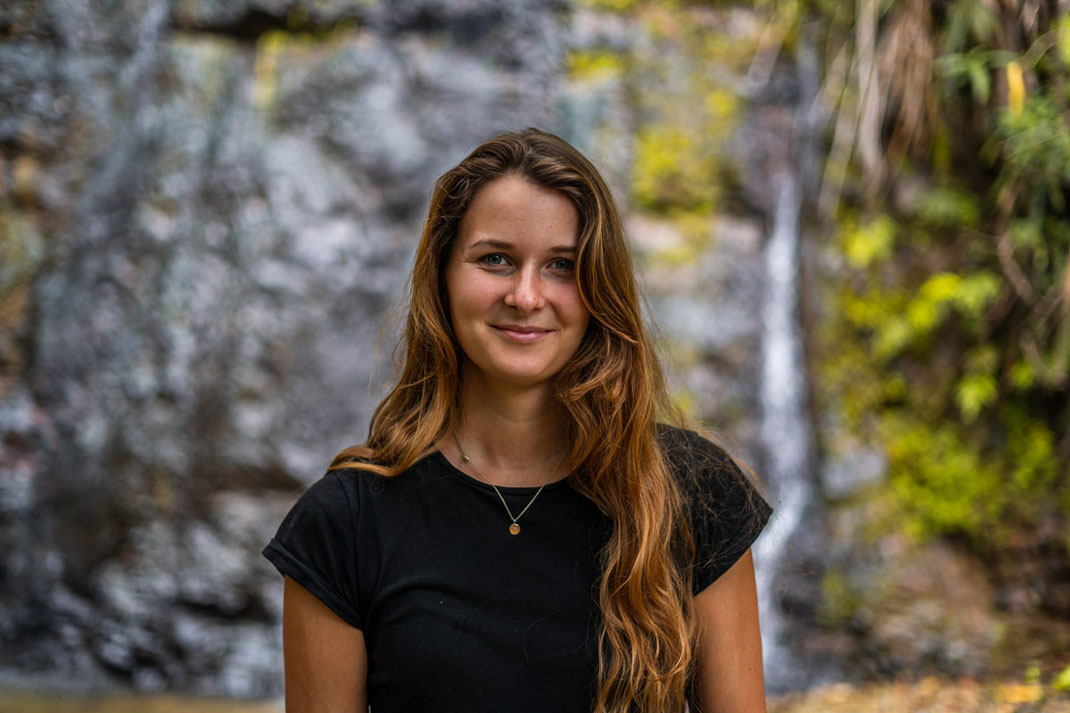 A woman with long brown hair smiles into the camera at Kaeng Nyui waterfall.