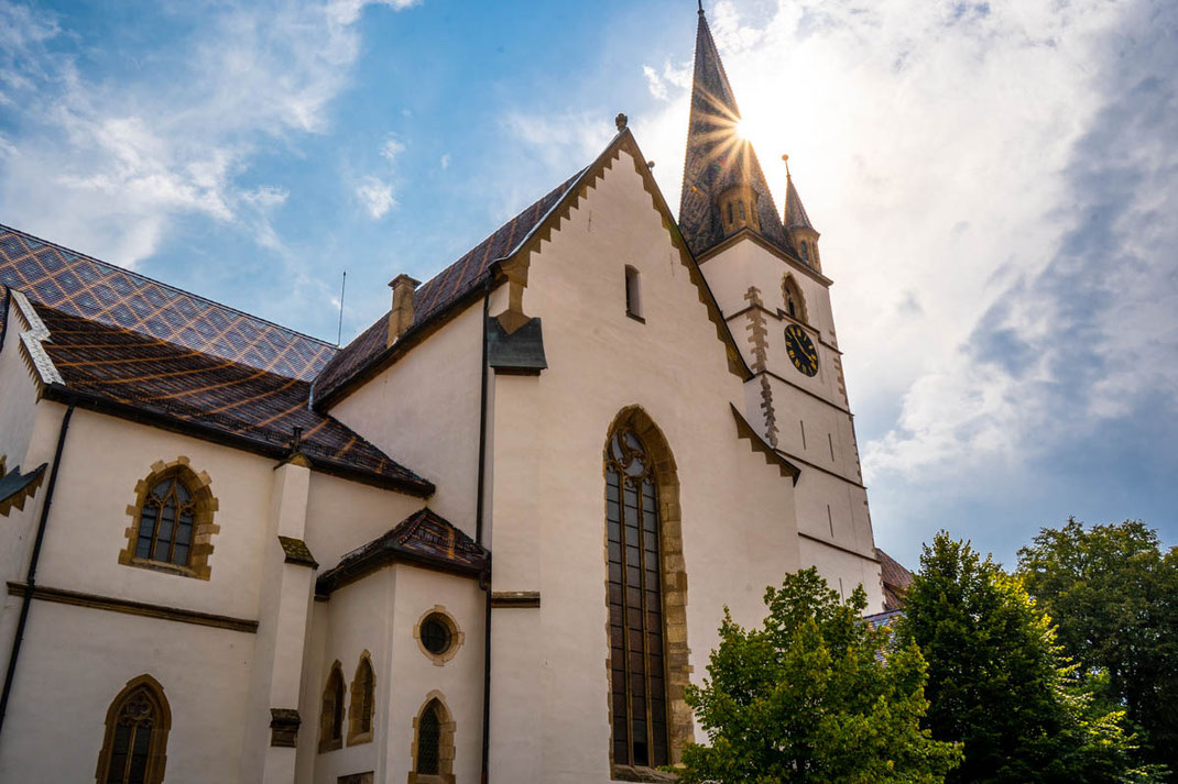 Die Sonne stahlt am malerischen Kirchturm der evangelischen Stadtkirche von Sibiu vorbei.