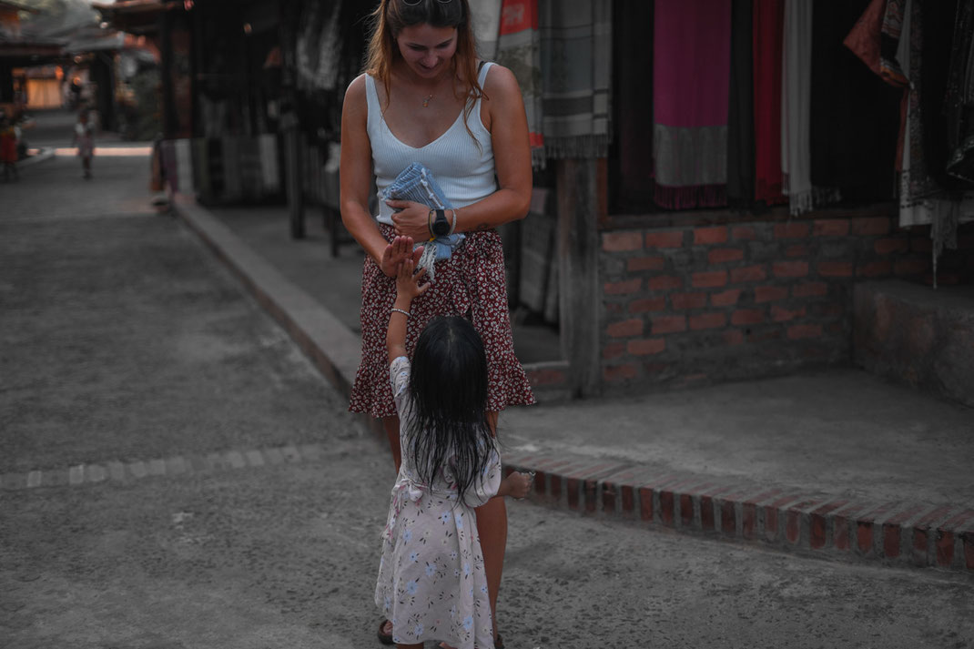 A small child in Ban Xang Hai claps the hand of a young woman.