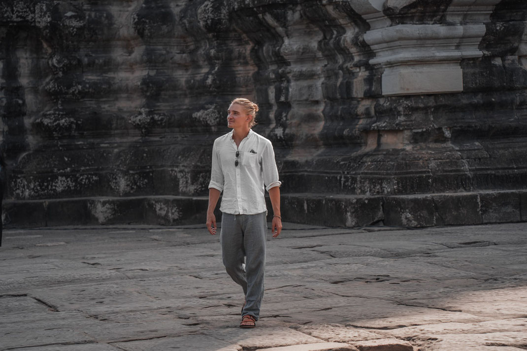 Ein Mann in einem weißen Hemd spaziert durch die Tempelanlagen von Angkor.