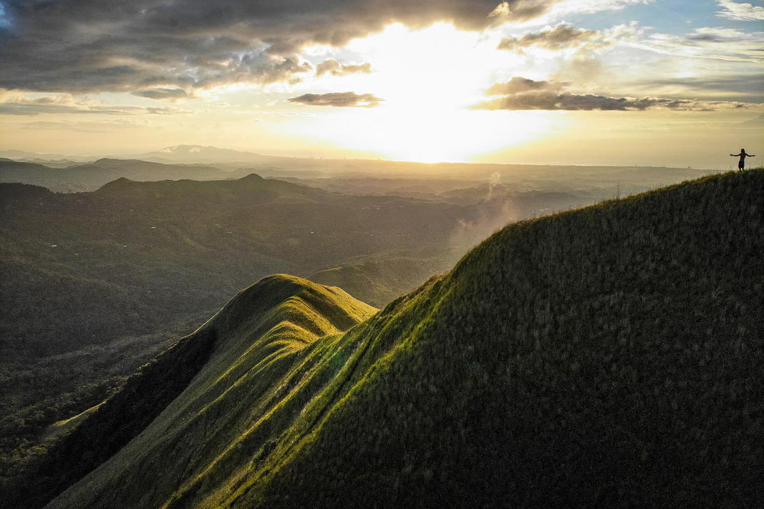 Un homme, les bras tendus, admire le lever du soleil sur le Cerro la Silla.