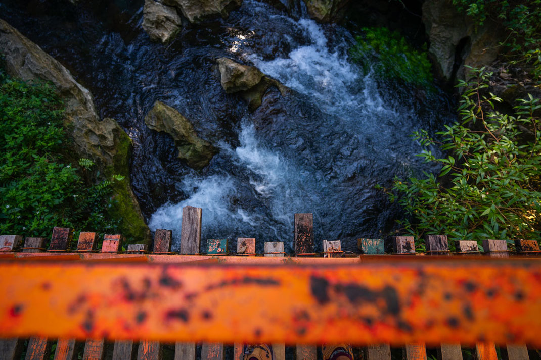 錆びたオレンジ色の橋が、透明な水をたたえた小さなプールに架かっている。