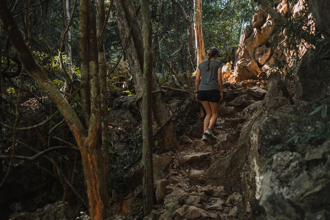 Une femme marche le long d'un étroit sentier qui monte vers un point de vue à Vang Vieng.