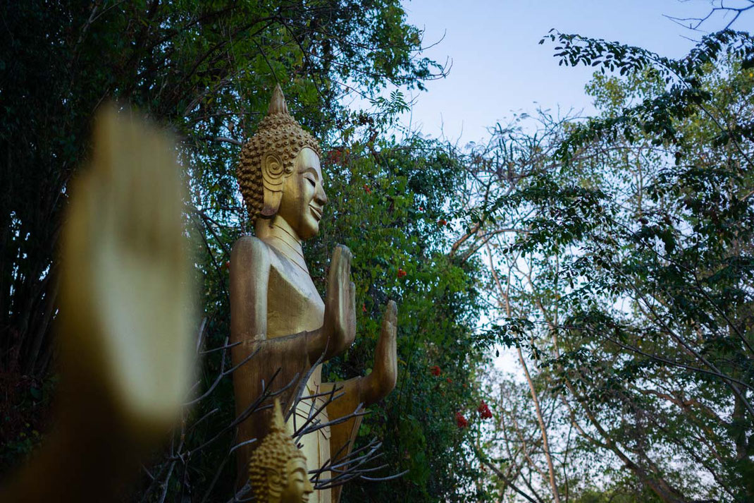 Una figura dorada de Buda de pie en el monte Phou Si por la mañana.