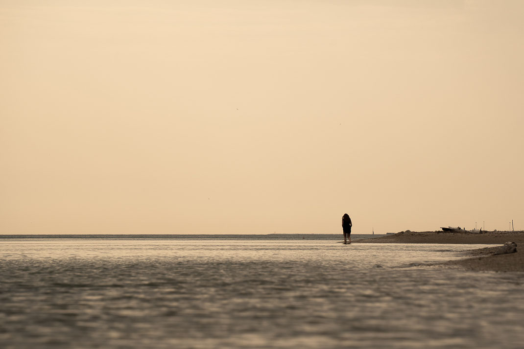Einsame Frau wandert am verlassenen Strand bei Fiorenzuola di Focara.