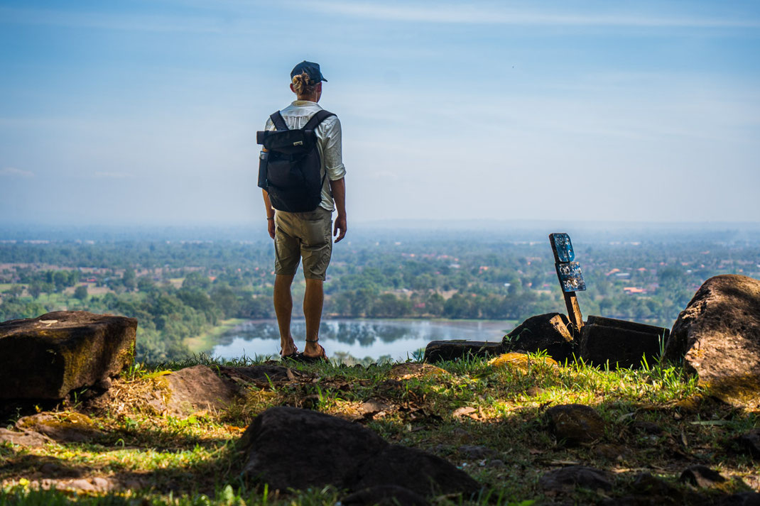 Au point le plus élevé, un homme regarde en bas l'ensemble du site du Vat Phou.