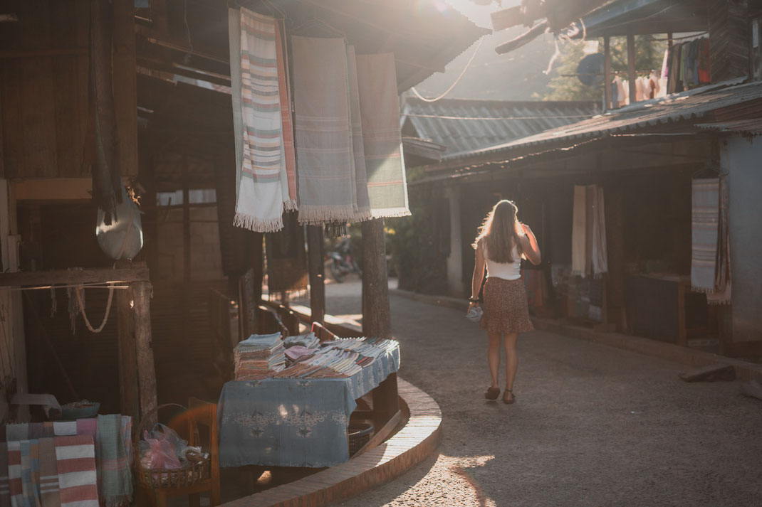Une jeune femme se promène dans le village de tissage de Ban Xang Hai au coucher du soleil.