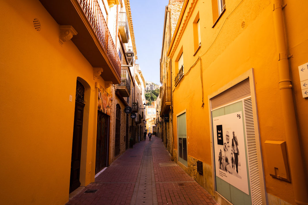 Eine Gasse mit gelben Häusern in der Stadt Begur am Morgen.