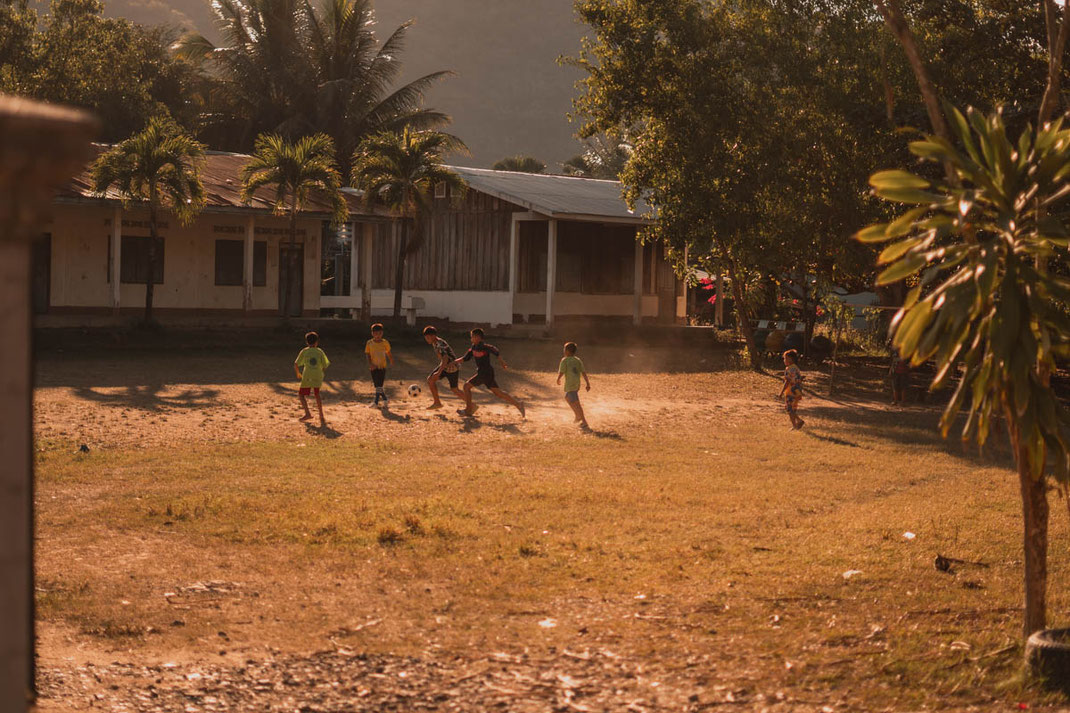 Children near Ban Xang Hai village playing soccer at sunset.