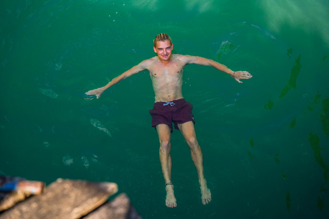 A man floats in a blue lagoon in Vang Vieng.