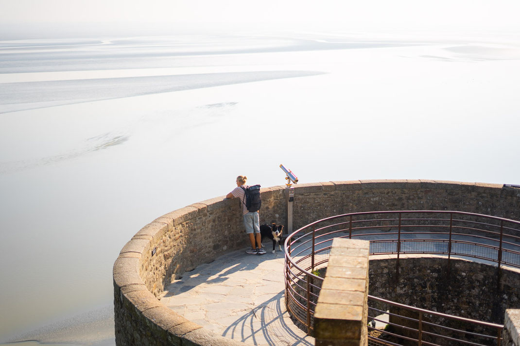 Ein Mann blickt von der Mauer des Mont-Saint-Michel auf das Meer hinaus.