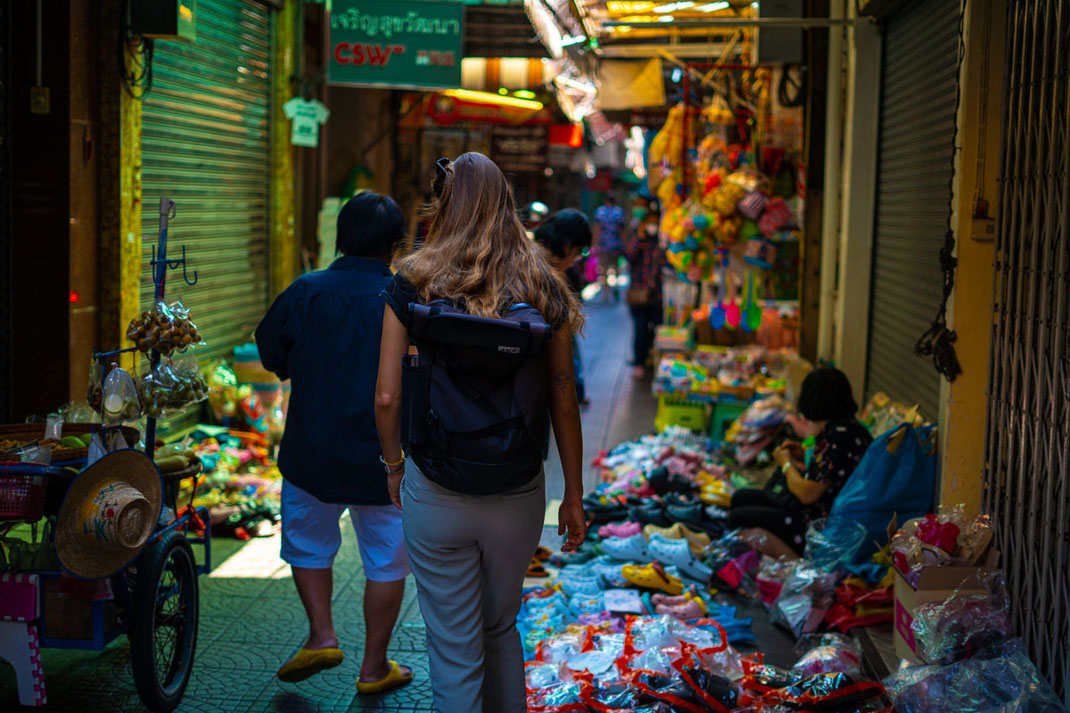 Une femme déambule dans les ruelles étroites de Chinatown, remplies de marchandises.