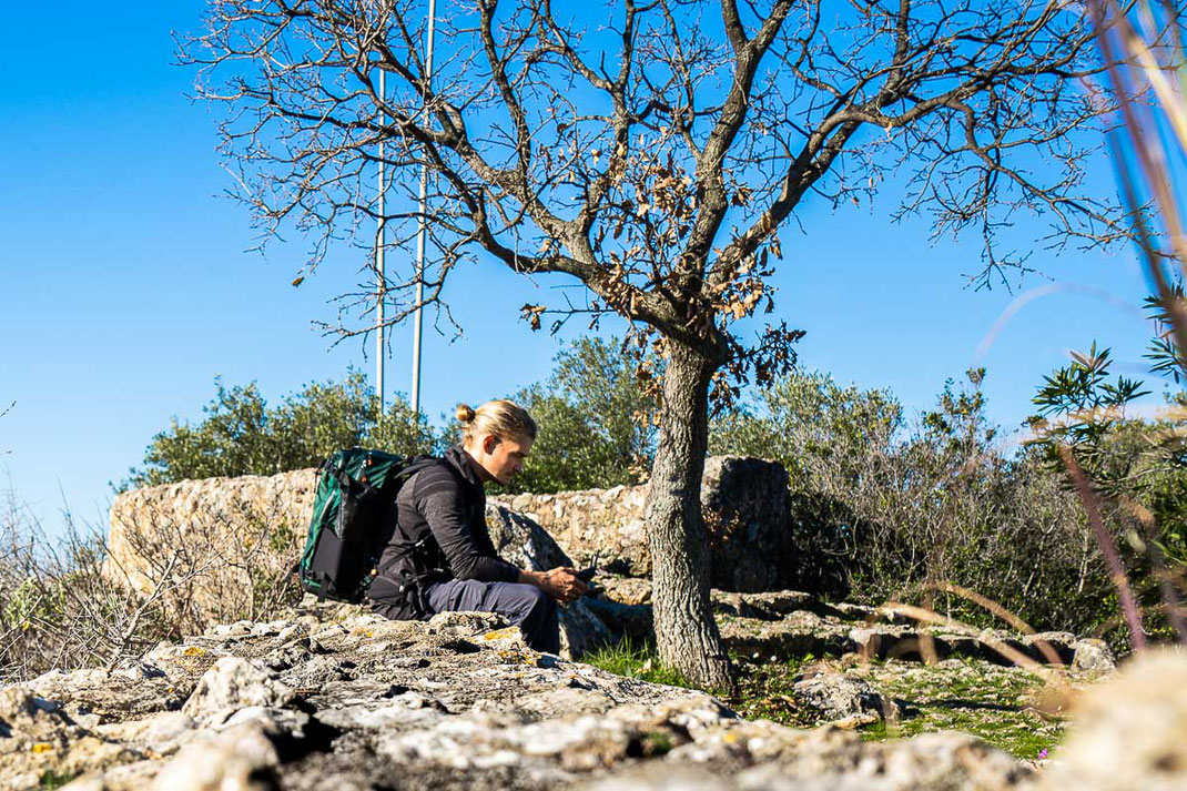 Mann sitzt auf der Burgmauer und lässt seine Drohne starten.