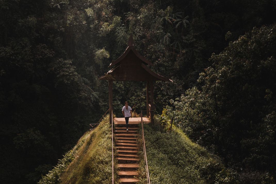 Una mujer sube una escalera hasta un mirador de la cascada de Tad Yuang.