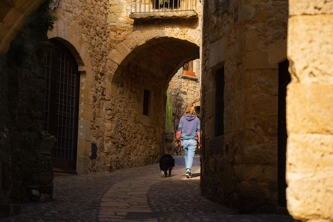 Eine Frau spaziert mit einen Hund durch die engen Gassen der Stadt Pals.