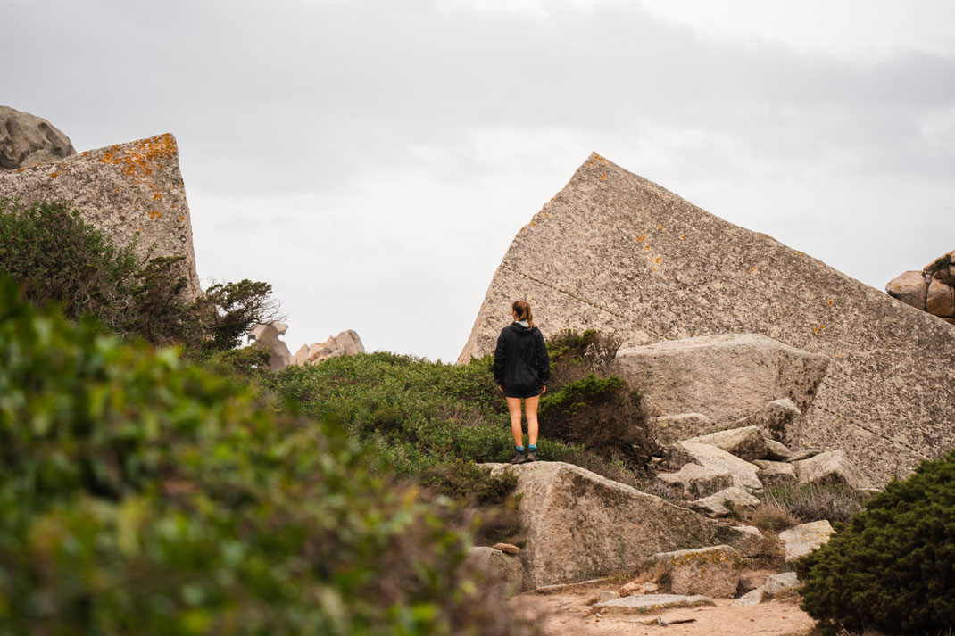 Eine Frau steht auf einen Felsen und blickt in die Ferne.