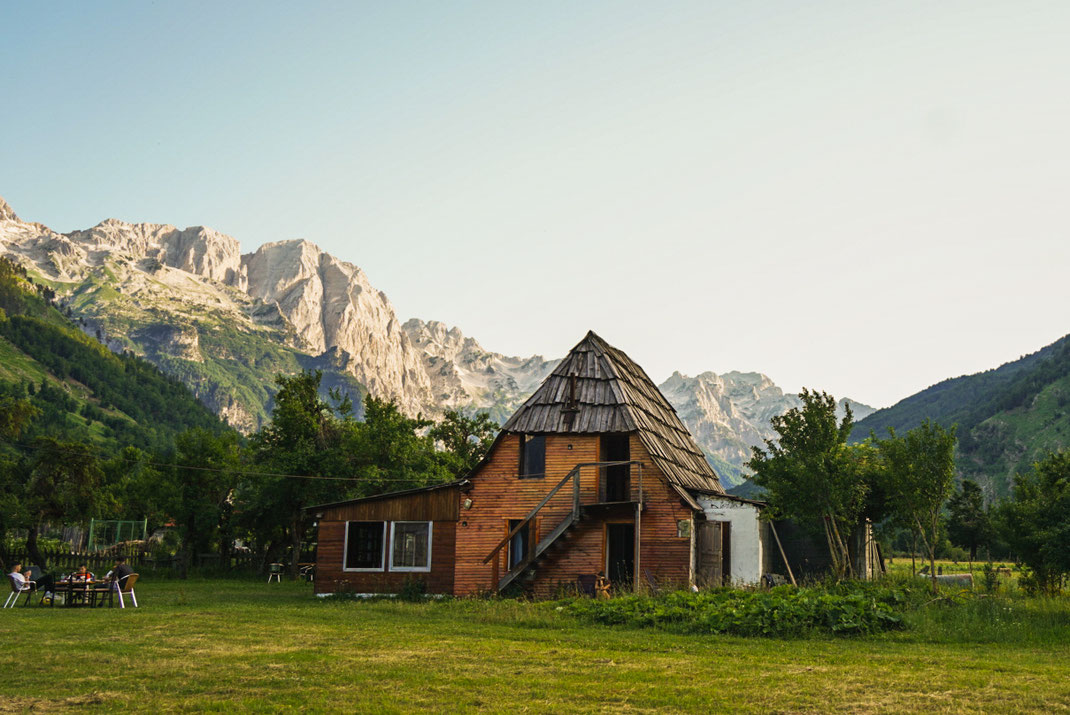 Kleine Hütte im entlegenen Valbona Tal mit schroffen Bergen im Hintergrund.