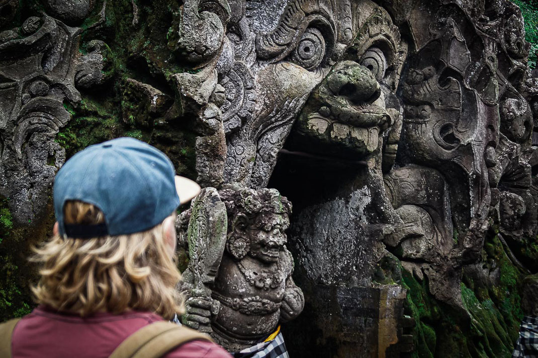 Man admires the entrance of the elephant grotto Goa Gajah.