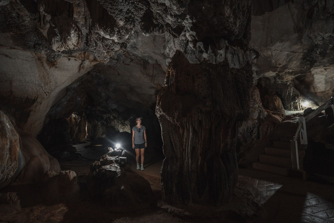 A woman stands in Tham Chang Cave and admires the stone formations.