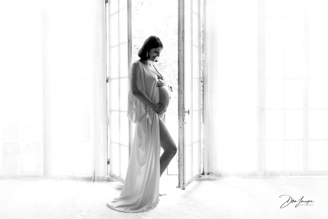 shooting grossesse ; future maman en contre-jour dans un espace lumineux, lumière naturelle, devant une fenêtre