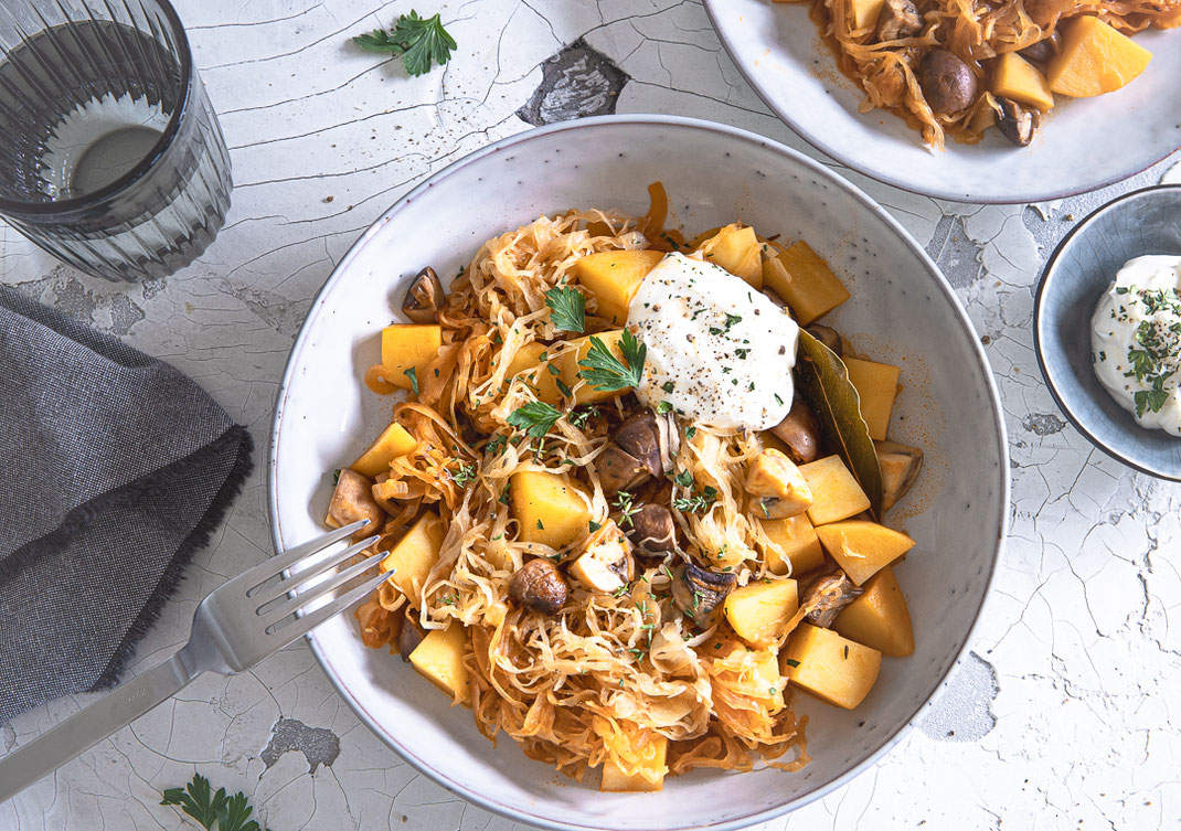 Deftiger vegetarischer Szegediner Kartoffelkraut-Eintopf mit Champignons, Kartoffeln und Sauerkraut in einer Schale serviert