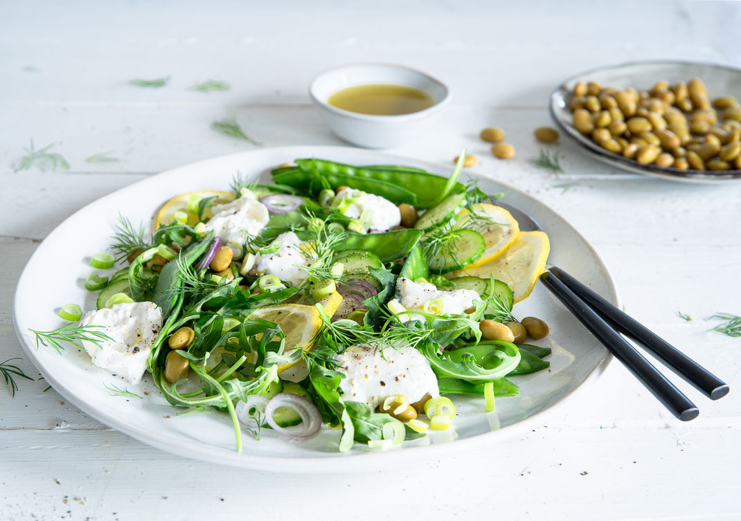 Frühlingssalat mit Rucola, Zuckererbsen, Edamame und Burrata auf einer Servierplatte