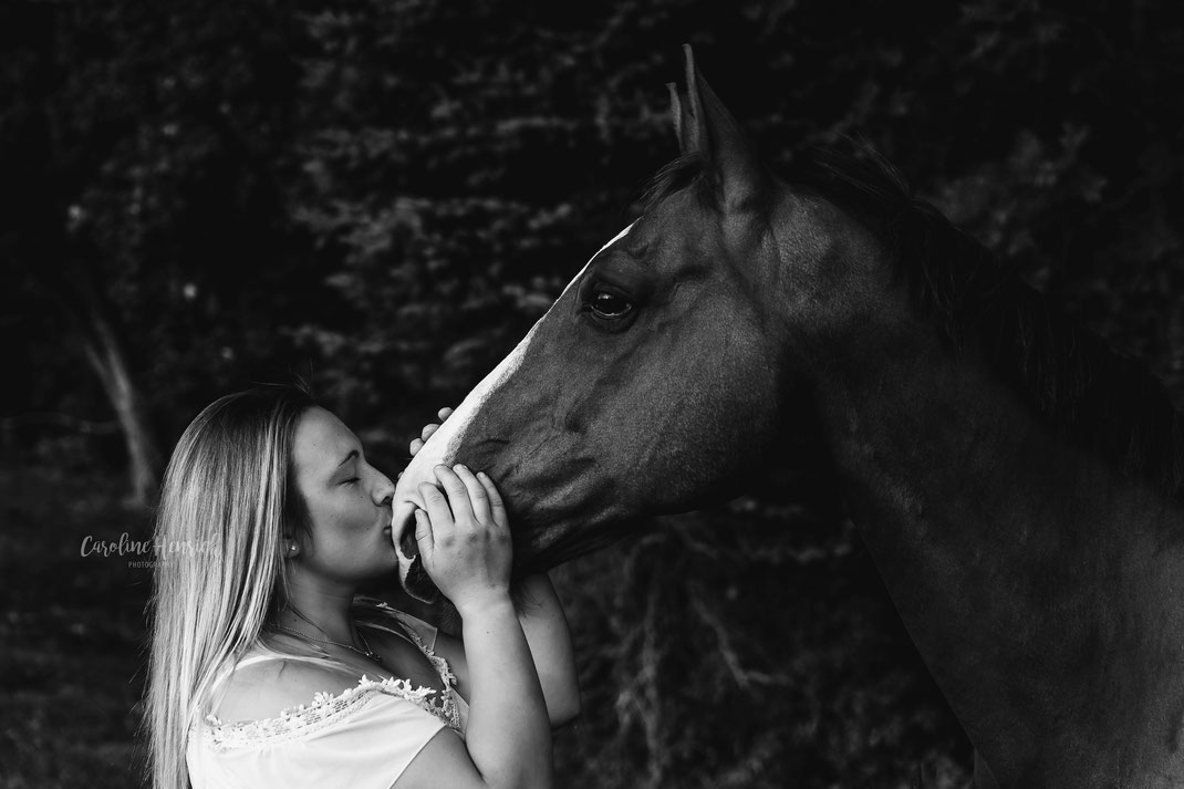 Ein großes Pferd wird von einer Frau auf die Schnauze geküsst.