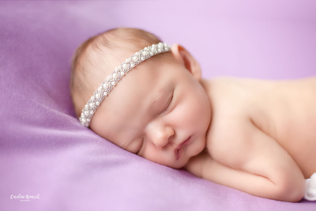 Neugeborenenfotoshooting Lauffen am Neckar Baby Mädchen auf lila Decke mit Perlen Stirnband