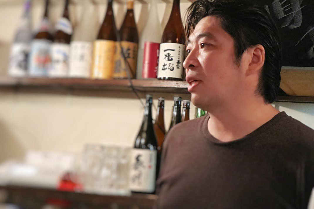 店主の竹見俊一郎さん。お客様と酒器について真剣に話している写真