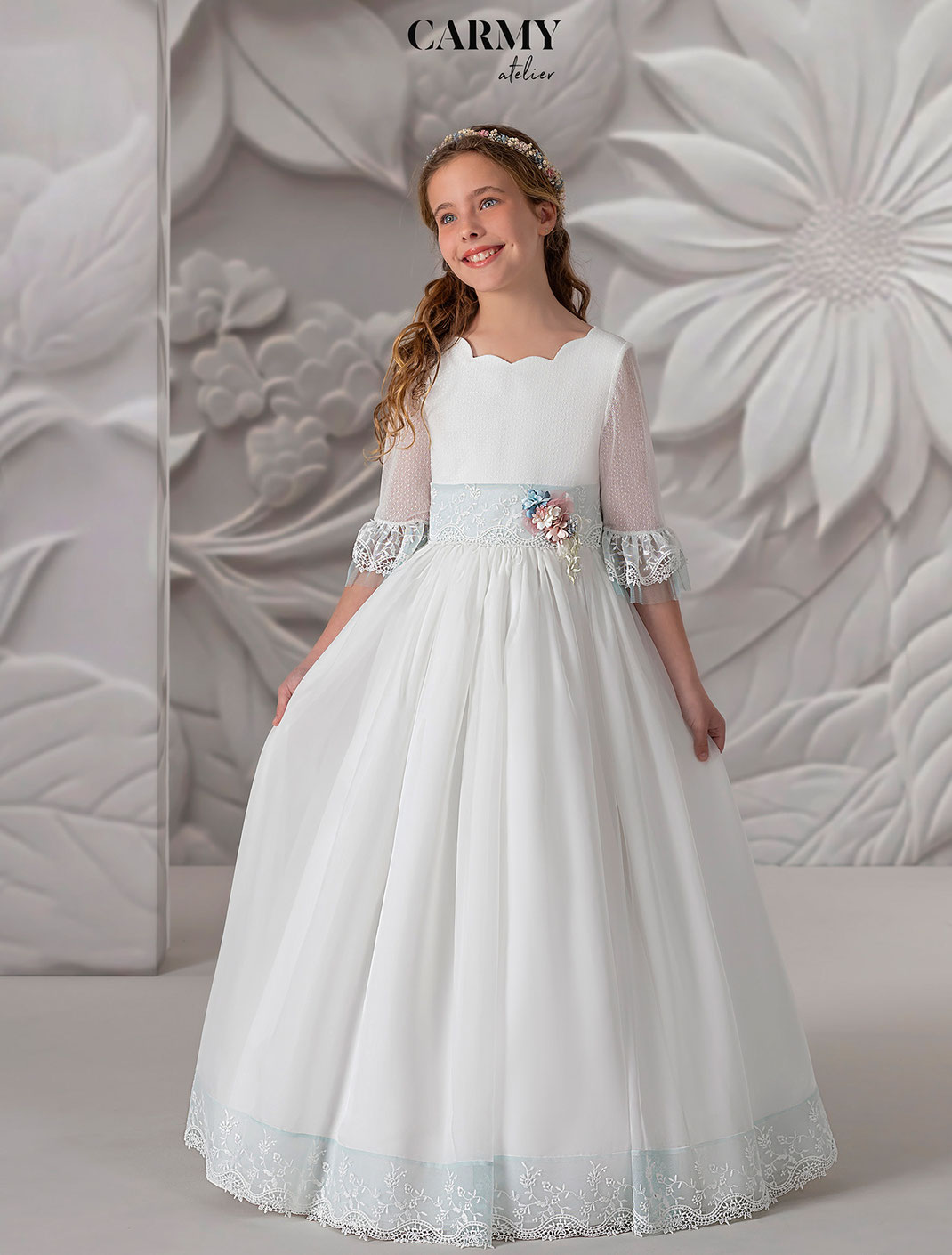 Mädchen trägt ein Kommunionkleid zur Erstkommunion aus zartem naturfarbenen Chiffon aus der Kollektion Carmy Kommunion 2025