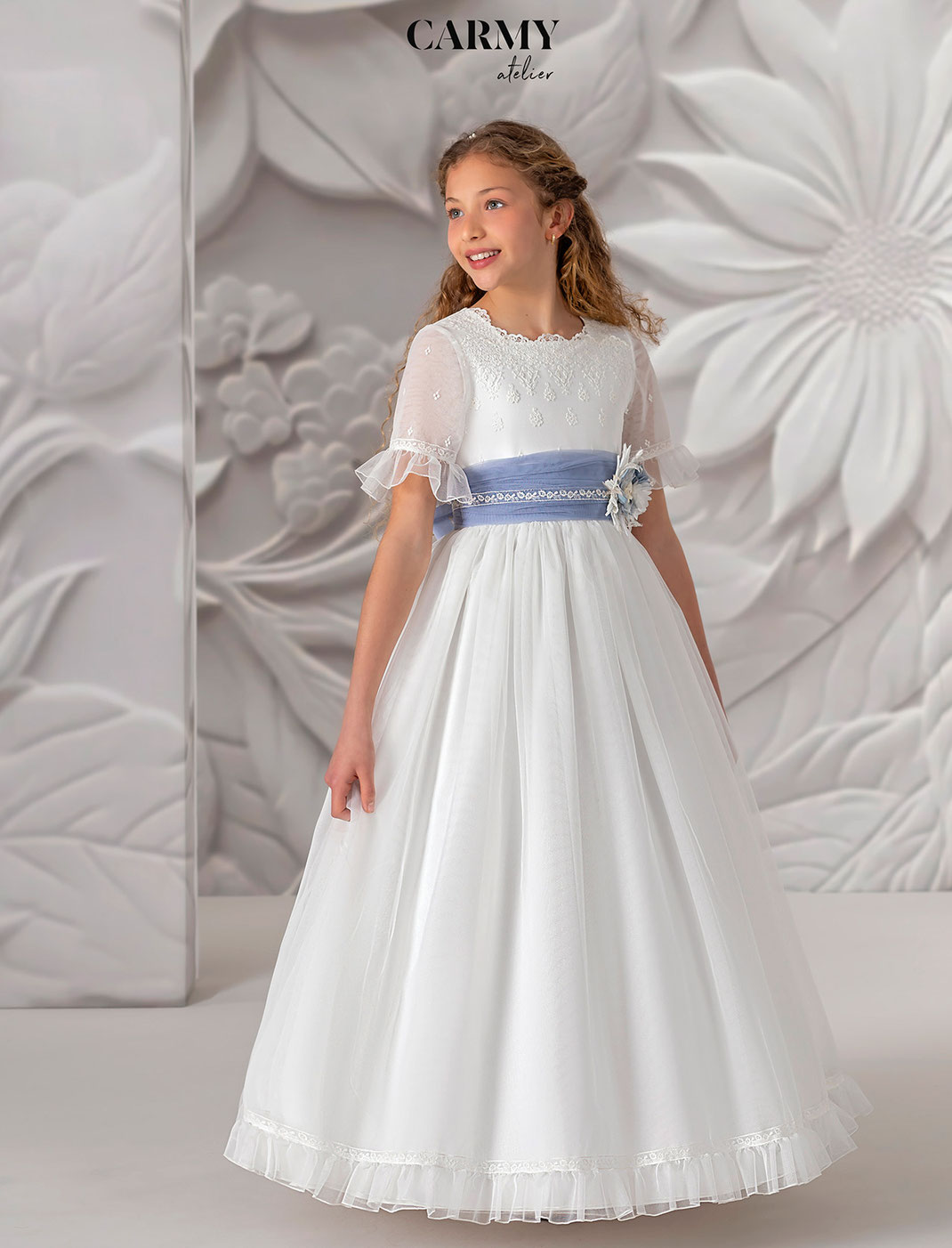 Mädchen trägt ein tolles weisses Kommunionkleid aus Chiffon aus der Kollektion Carmy Kommunion 2025