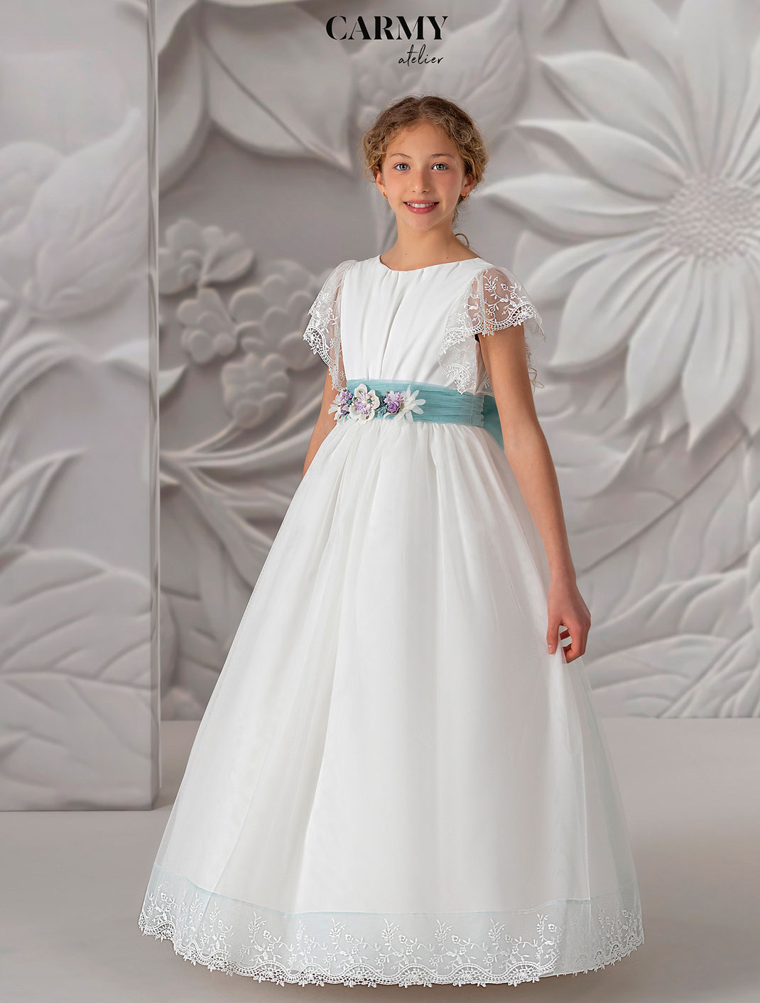 Mädchen trägt ein wunderschönes Kommunionkleid aus der Kollektion Carmy Kommunion 2025