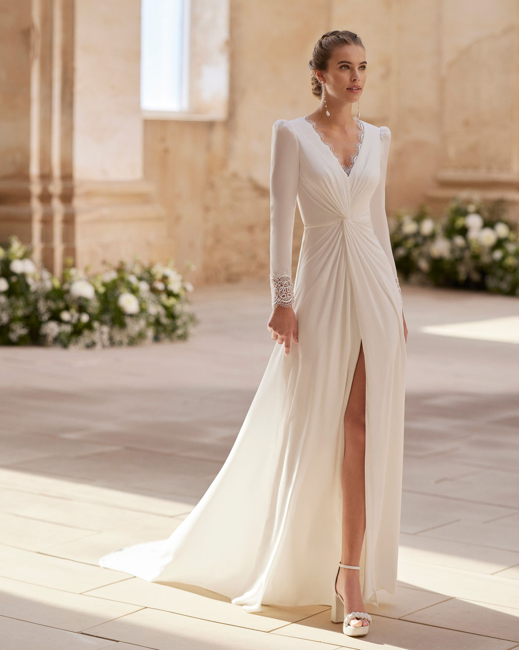 Junge Frau mit Brautschuhen und Brautschmuck trägt das Hochzeitskleid Haziel aus der Alma Novia Kollektion 2025