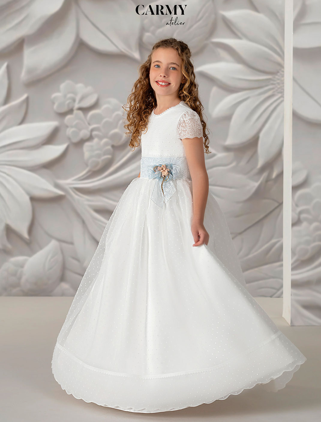 Mädchen trägt ein elegantes Kommunionkleid aus der Carmy Kommunion 2025 Kollektion