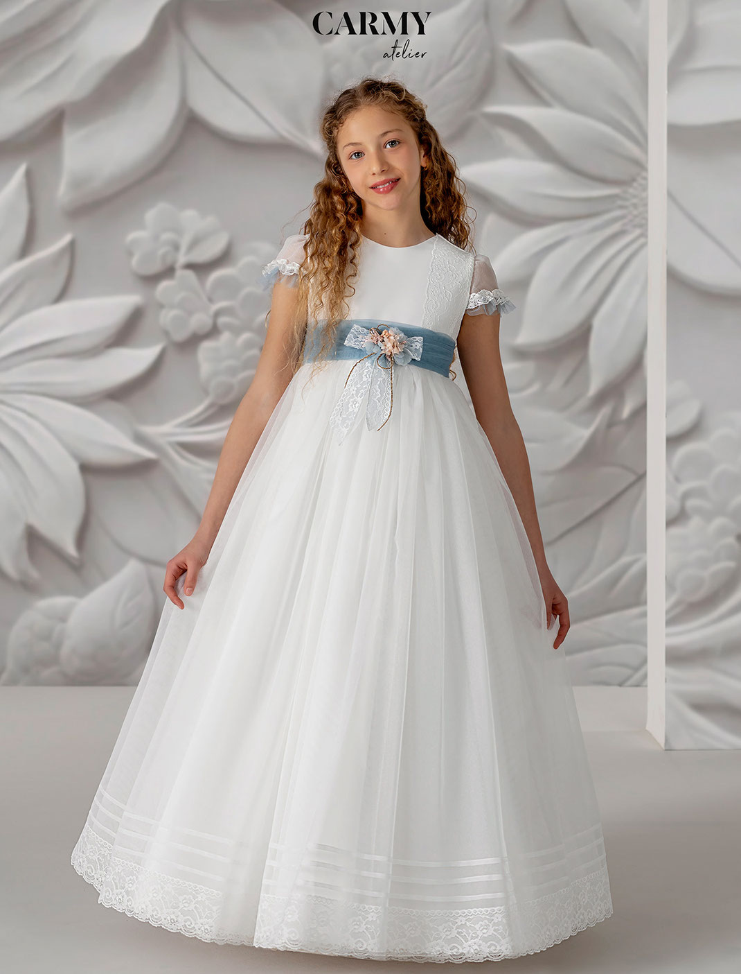 Mädchen trägt ein elegantes Kommunionkleid aus der Carmy Kommunion 2025 Kollektion