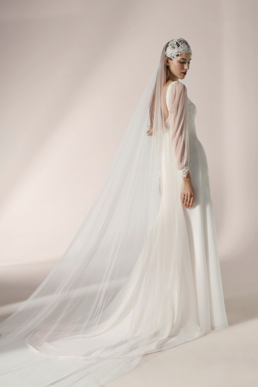 Model trägt ein Georgette-Chiffon-Brautkleid mit Ärmeln aus Seidentüll und matter Spitzenborte von Jesus Peiro
