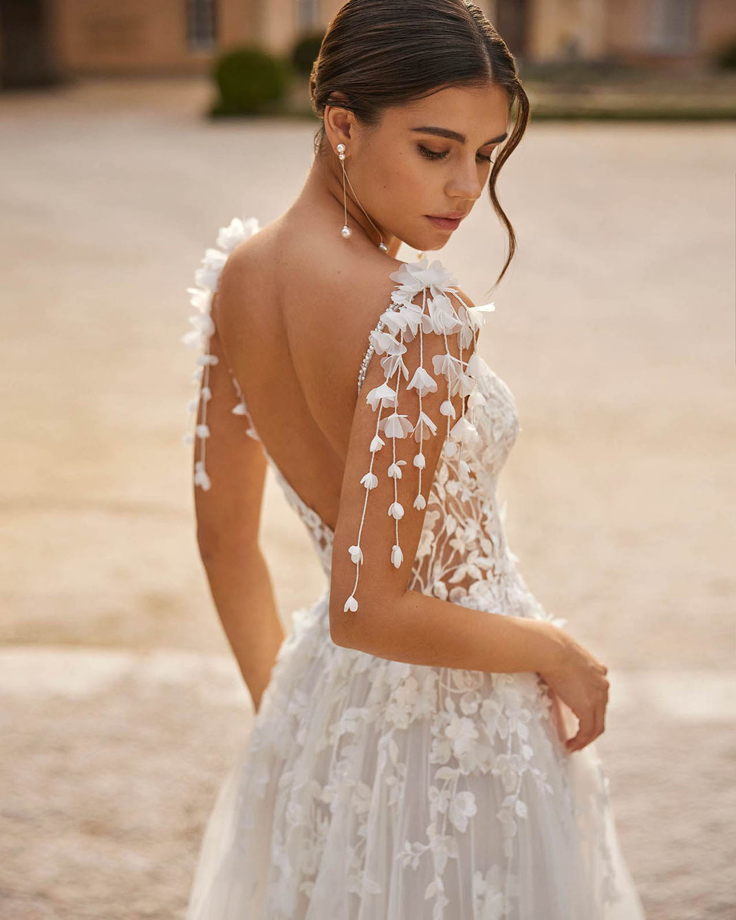 Junge Frau vor einem Anwesen trägt das Brautkleid Vals von Rosa Clará Dreams