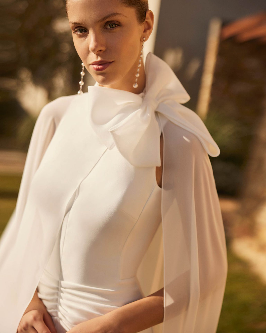 Porträt einer Frau mit langen Ohrringen die das Brautkleid Zabi aus der Aire Boho Kollektion 2026 trägt