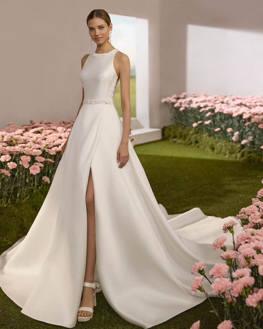 Junge elegante Frau in einem Blumenmeer trägt das Brautkleid Rena von Rosa Clará Couture