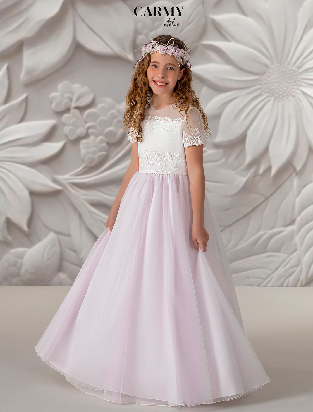 Mädchen trägt ein bezauberndes Kommunionkleid aus zartem Tüll Kollektion Carmy Kommunion 2025