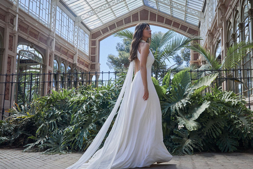 Schöne Frau vor einer Palme und exotischen Pflanzen in Barcelona trägt ein Jesus Peiro Brautkleid