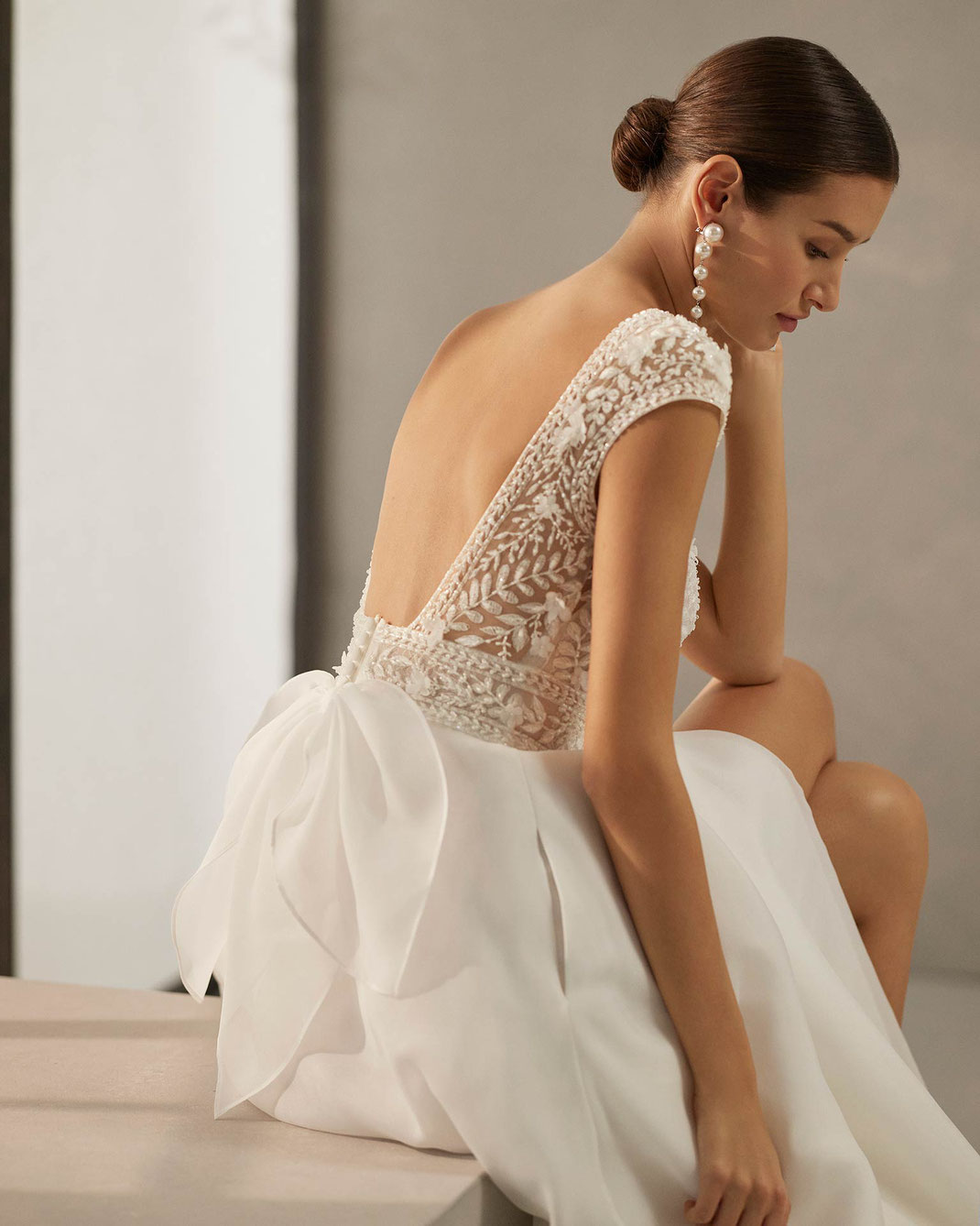 Frau sitzt im Studio auf einer Stufe und trägt das Brautkleid Cecilia aus der Rosa Clará Soft Kollektion 2025