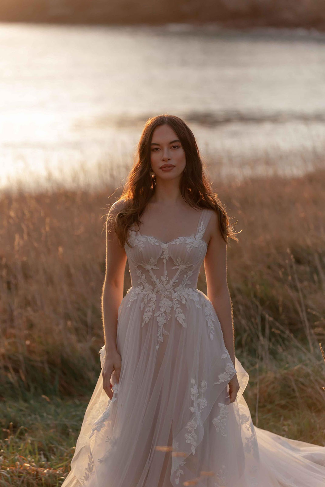 Frau in der Nähe eines romantischen Sees trägt das Madi Lane Brautkleid Kelsey