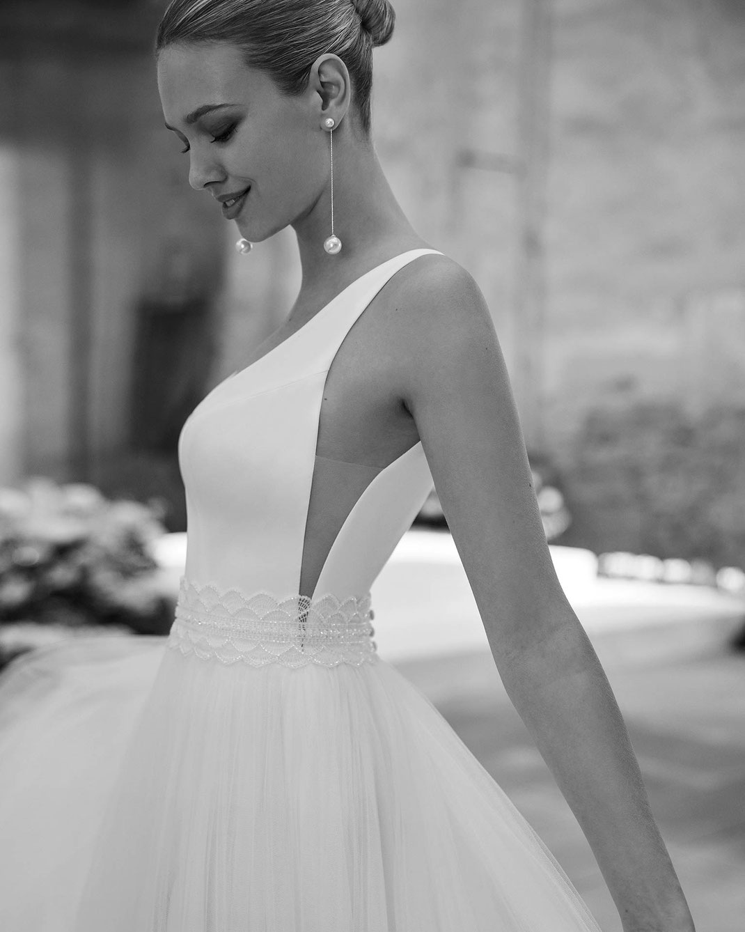 Junge Frau trägt elegante lange Ohrringe und das Brautkleid Melis aus der Aire Barcelona Kollektion 2026