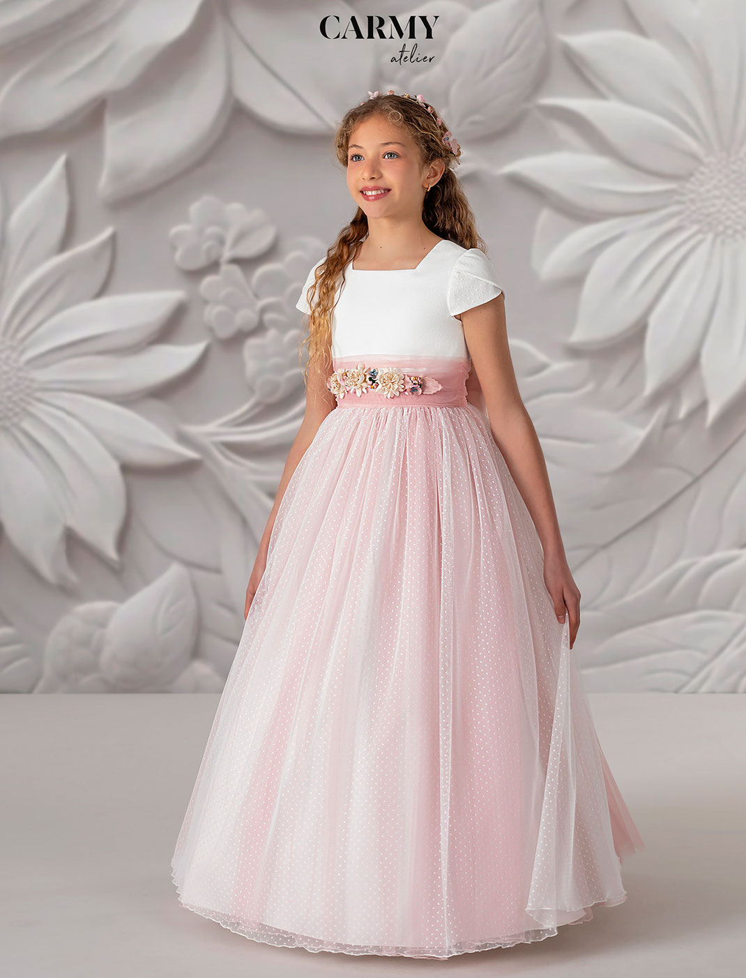 Mädchen mit Haarschmuck trägt ein Carmy Kommunionkleid