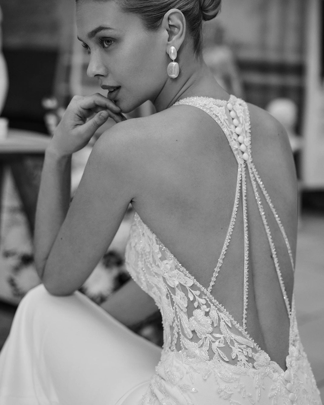 Junge elegante Frau mit schönem Rücken trägt das Brautkleid Maribel aus der Aire Barcelona Kollektion 2026