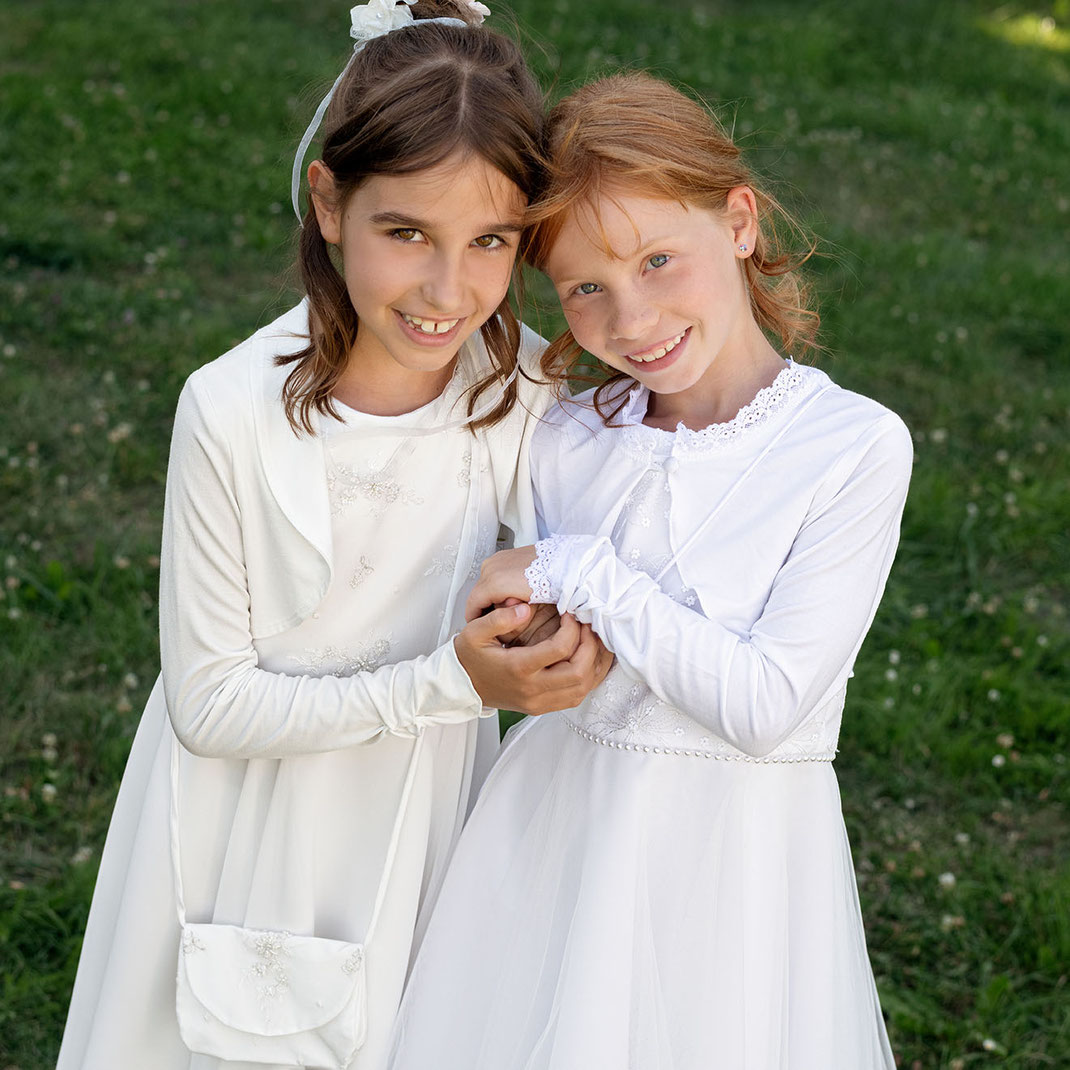 Zwei lachende Mädchen tragen Kommunionkleider der Marke Monny