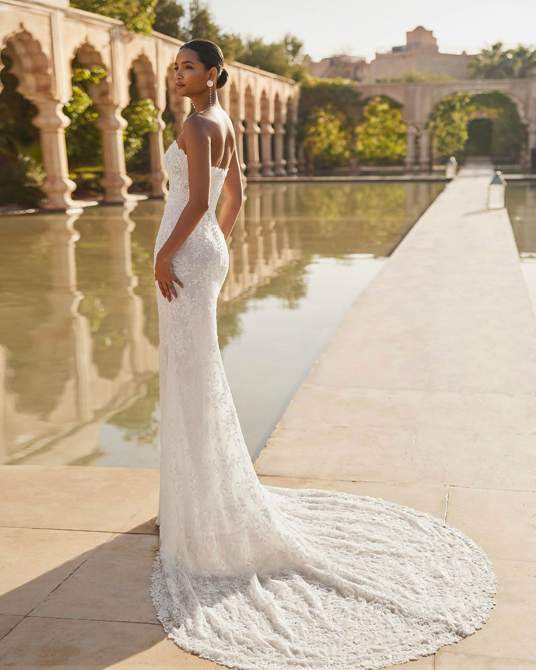 Rosa Clara Brautkleid Olmeda getragen von einer jungen eleganten Frau vor einem luxuriösen Pool