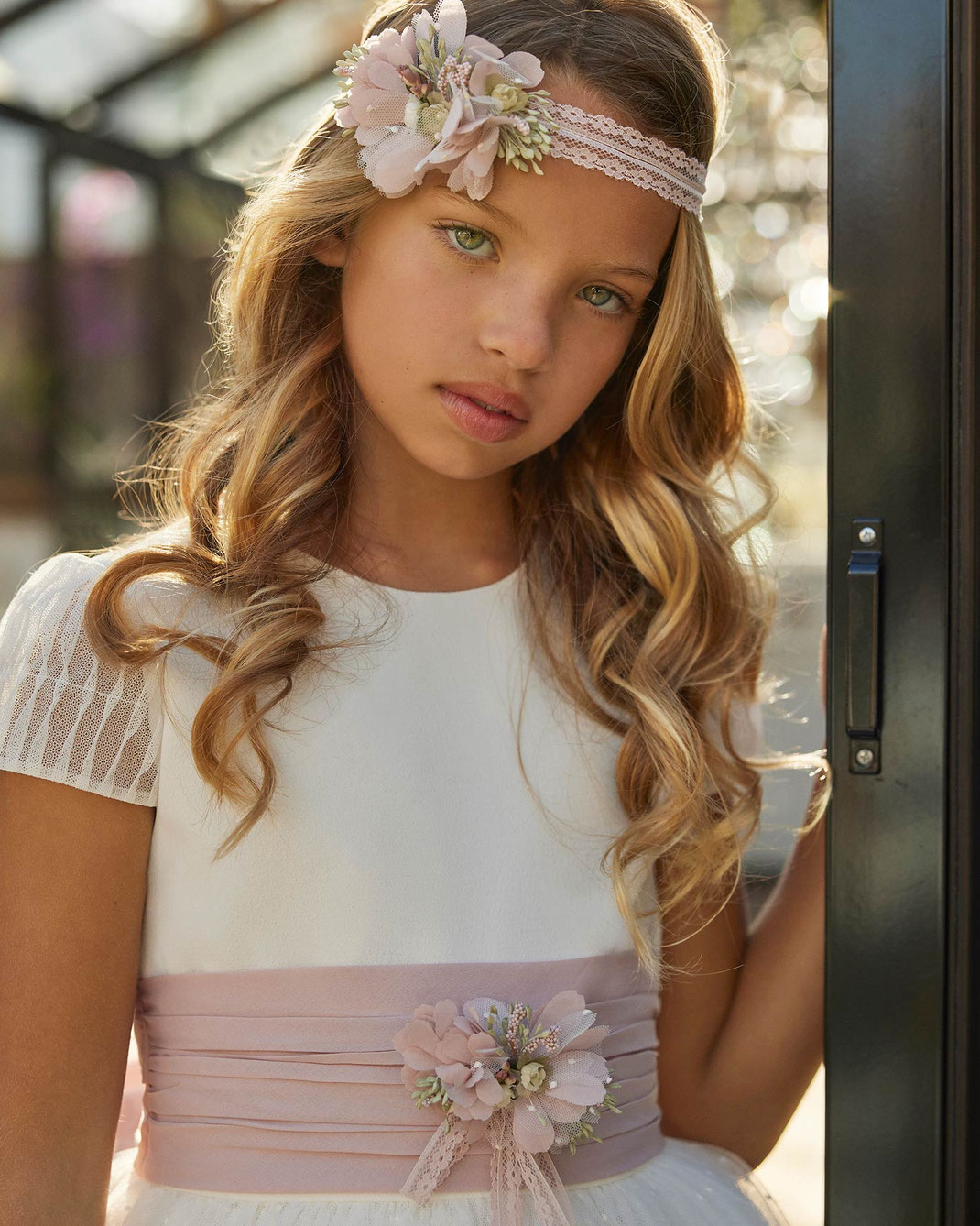 Junges Mädchen mit Haarschmuck trägt ein Kommunionkleid von Rosa Clará First